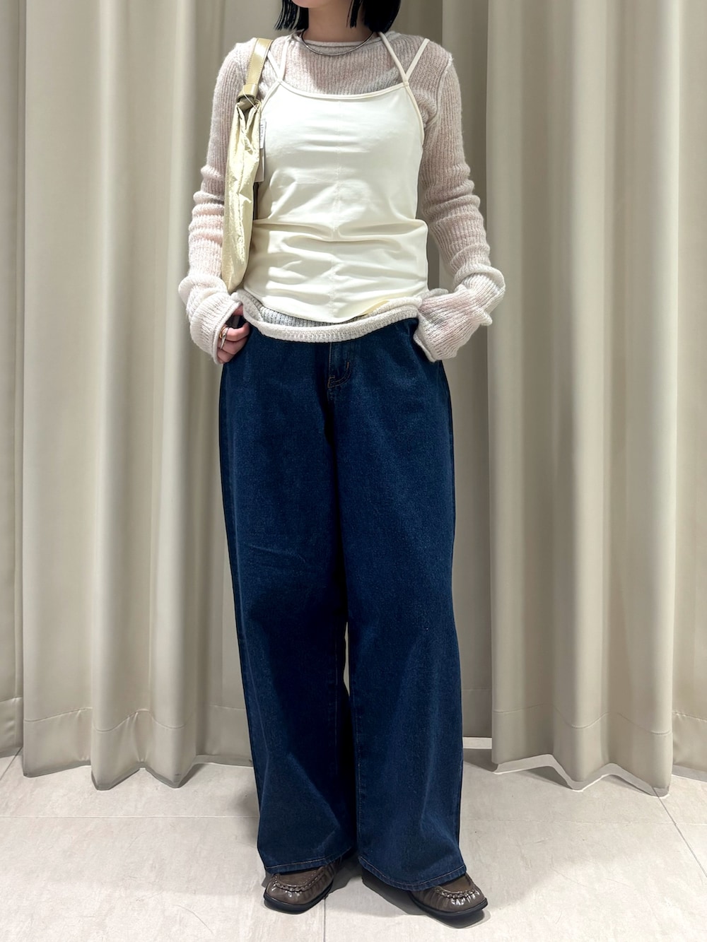 ホワイト系のニット/セーター、ブルー系のデニムパンツ、イエロー系のハンドバッグを着用したレディースの秋コーディネートの2枚目の写真