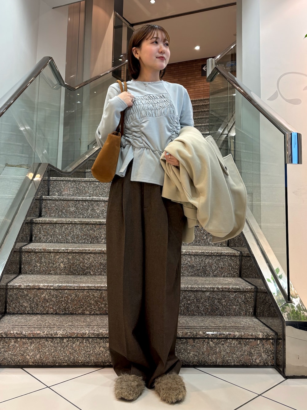 ブルー系のTシャツ/カットソー、イエロー系のボストンバッグ、ベージュ系のその他アウターを着用したレディースの冬コーディネートの2枚目の写真