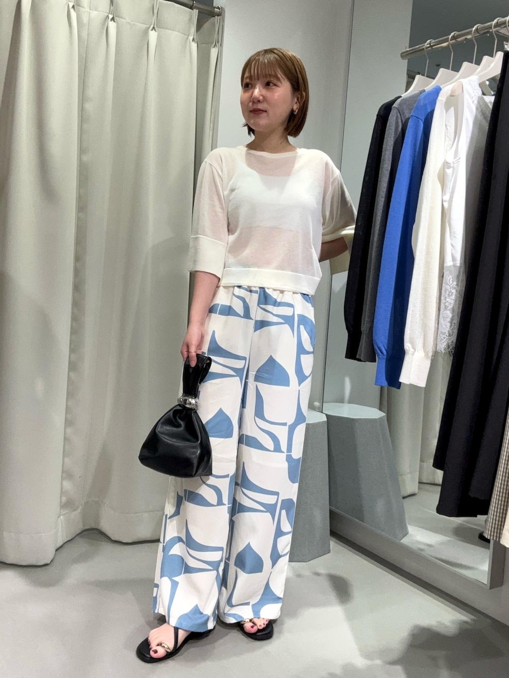 ブルー系のその他パンツ、ブラック系のハンドバッグ、ホワイト系のニット/セーターを着用したレディースの夏コーディネートの3枚目の写真