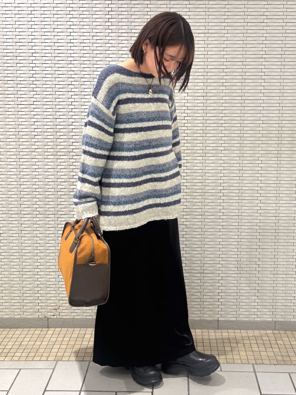 ブルー系のニット/セーター、ブラック系のスカート、イエロー系のボストンバッグを着用したレディースの秋コーディネートの3枚目の写真