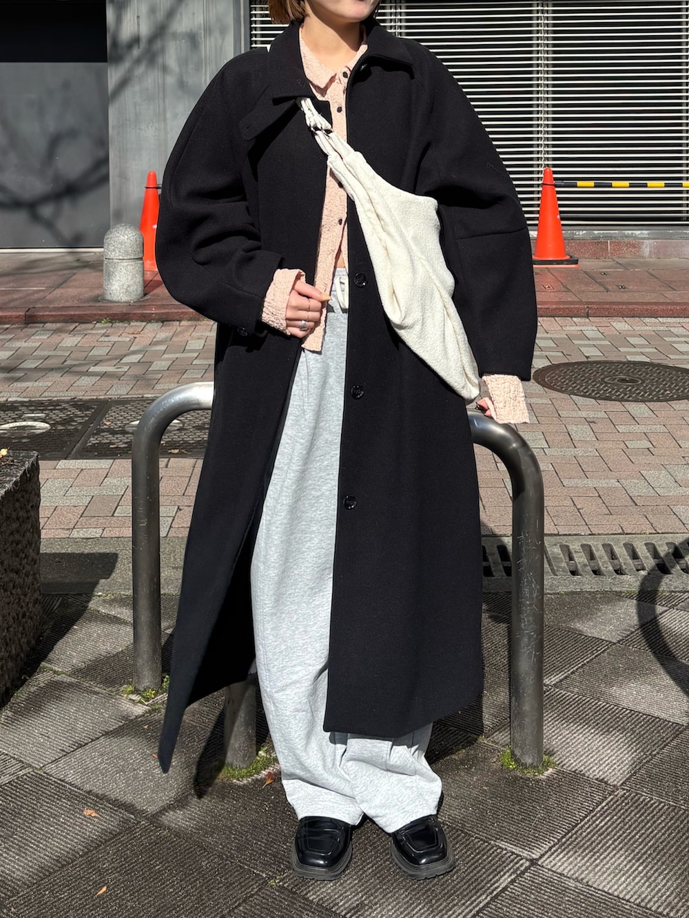 ピンク系のシャツ/ブラウス、グレー系のその他パンツ、ブラック系のステンカラーコートを着用したレディースの冬コーディネートの3枚目の写真