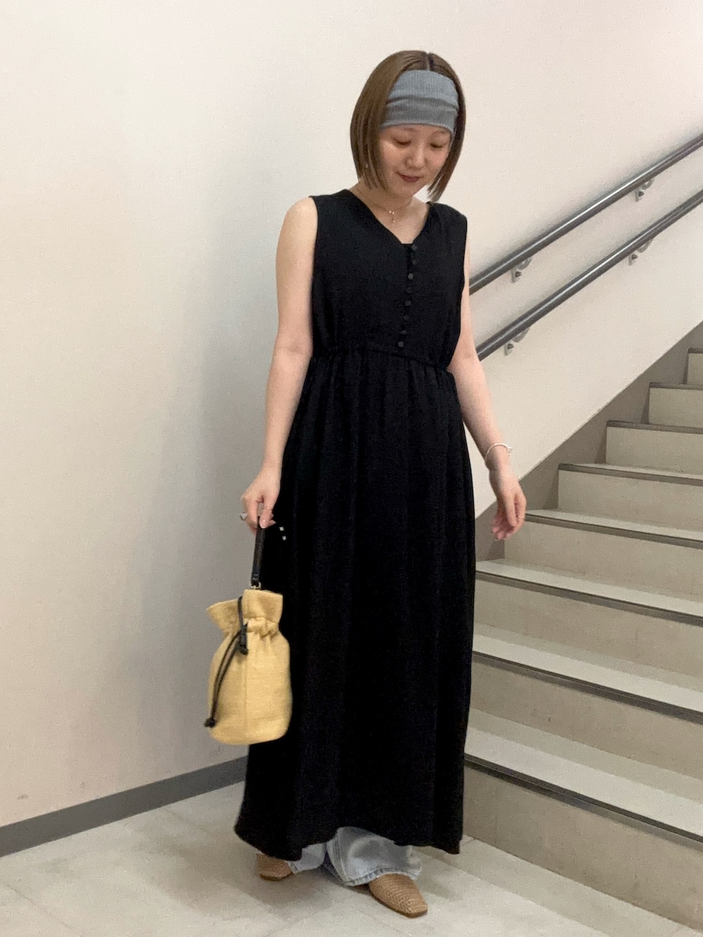 ブラック系のワンピース、ブルー系のデニムパンツ、ベージュ系のショルダーバッグを着用したレディースの夏コーディネートの2枚目の写真