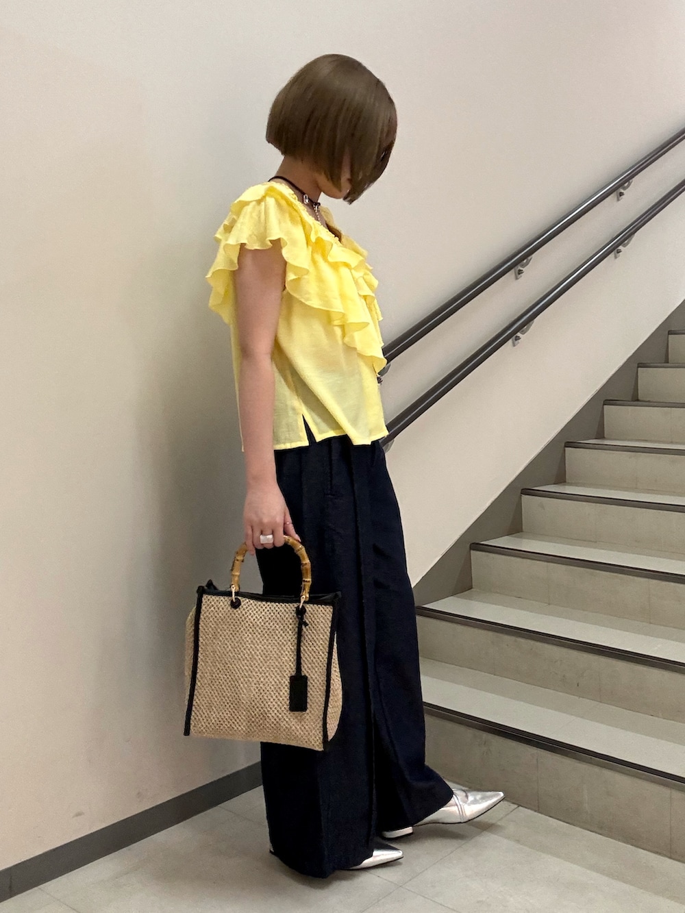 イエロー系のシャツ/ブラウス、シルバー系のパンプス、ブラック系のショルダーバッグを着用したレディースの春コーディネートの3枚目の写真