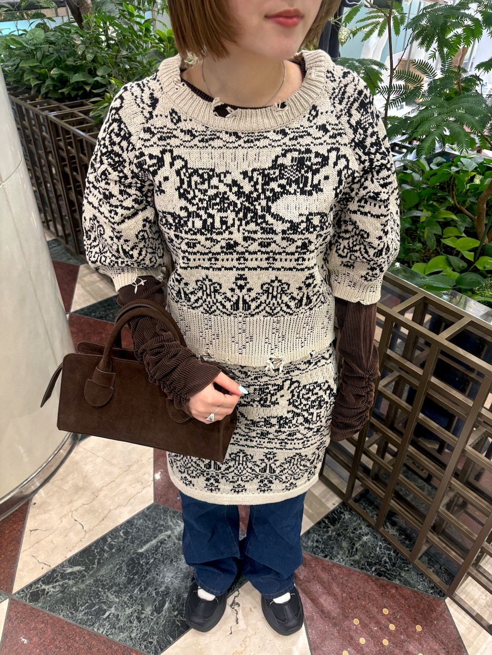 ベージュ系のニット/セーター、ベージュ系のスカート、ブルー系のデニムパンツを着用したレディースの冬コーディネートの4枚目の写真