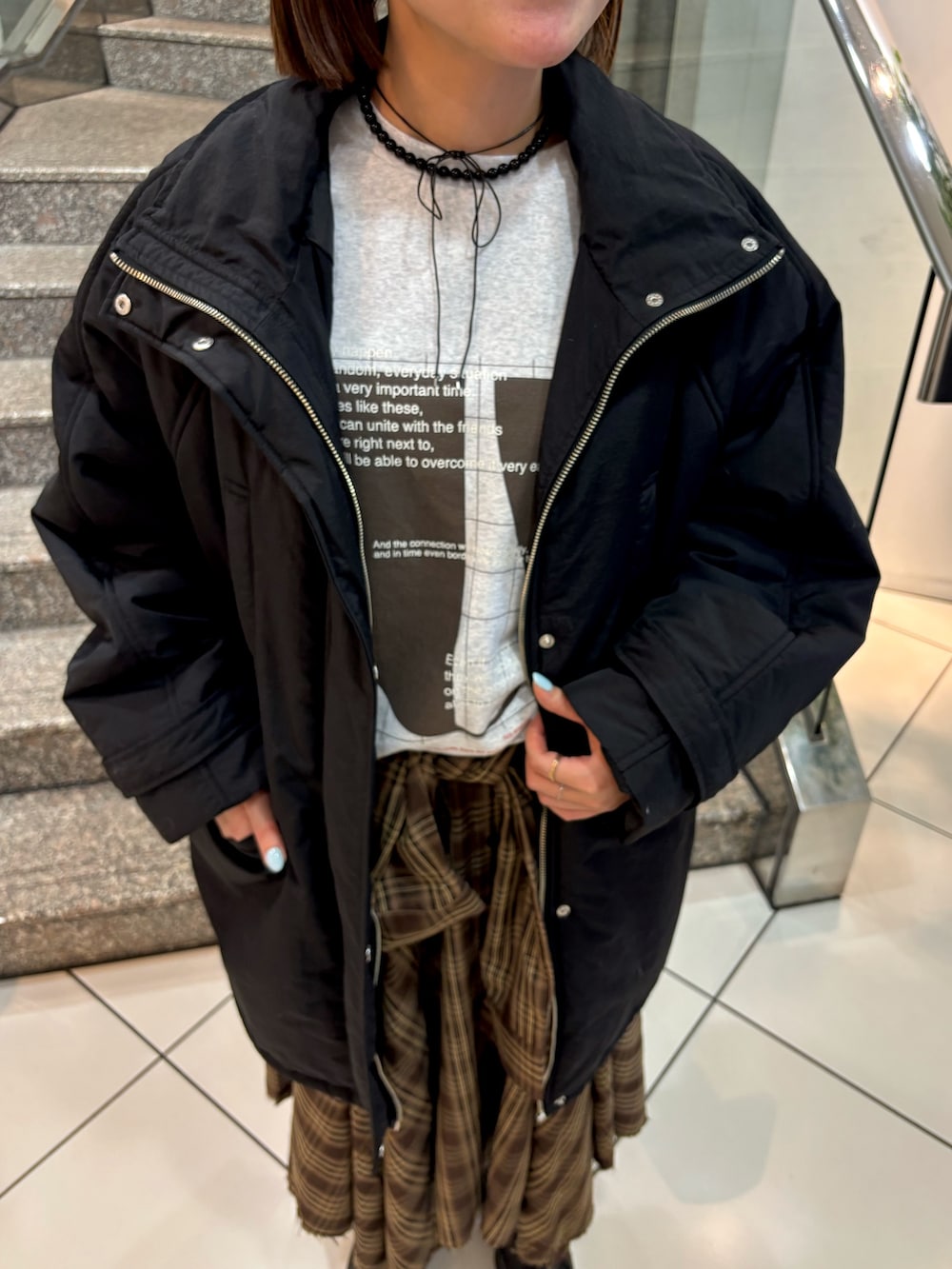 グレー系のTシャツ/カットソー、ブラウン系のスカート、ブラック系のダウンジャケット/コートを着用したレディースの冬コーディネートの5枚目の写真