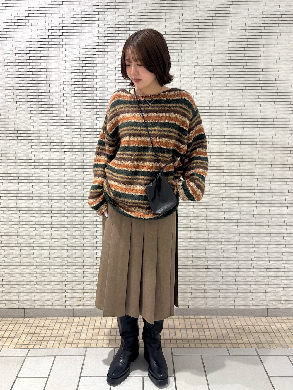 ブラック系のショルダーバッグ、ブラウン系のスカート、ブラウン系のニット/セーターを着用したレディースの秋コーディネートの3枚目の写真