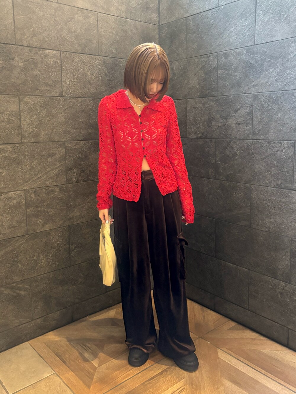 レッド系のニット/セーター、ブラウン系のその他パンツ、ホワイト系のハンドバッグを着用したレディースの冬コーディネートの5枚目の写真