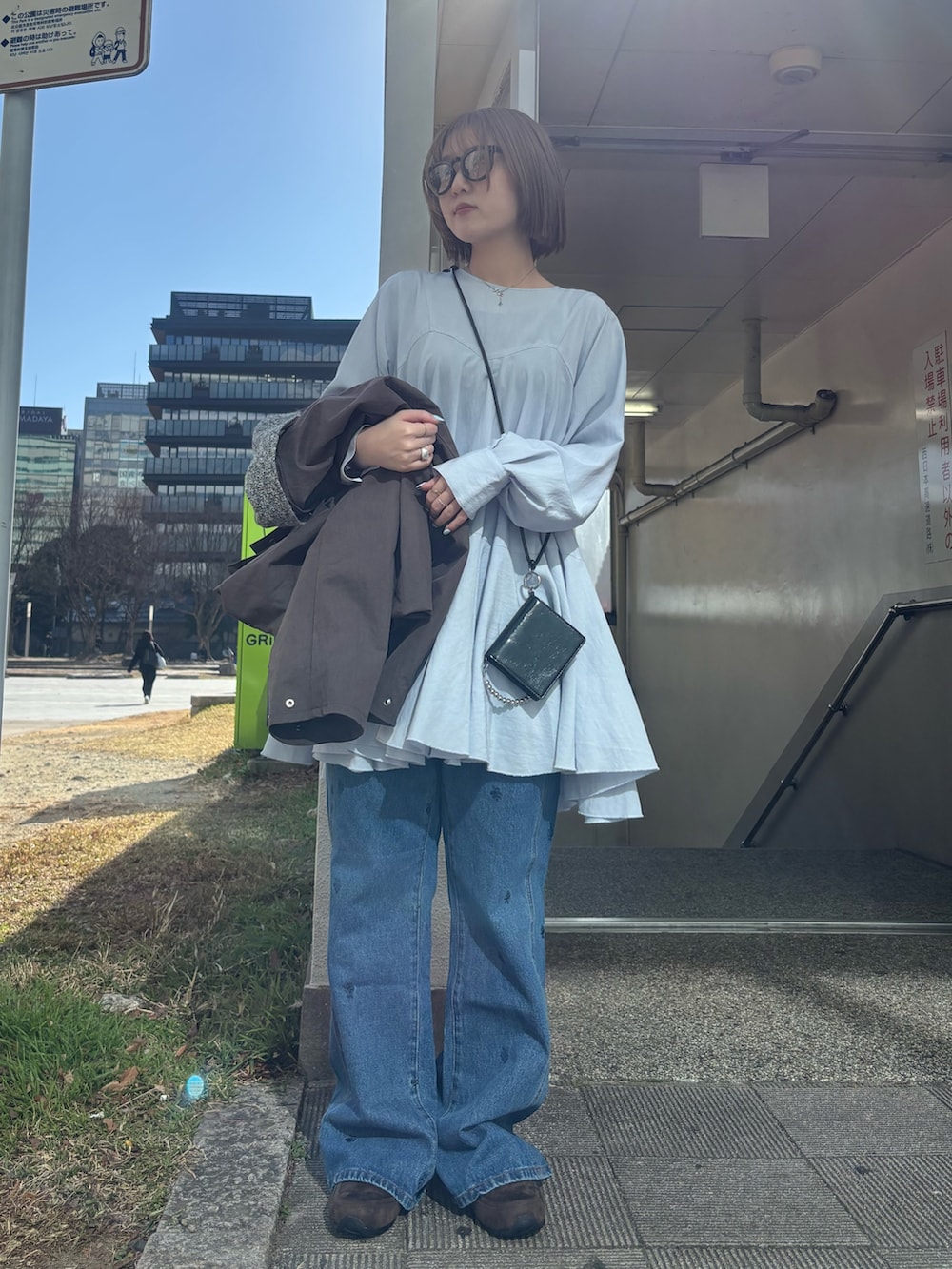 ブラウン系のブルゾン、ブルー系のワンピース、グレー系のスニーカーを着用したレディースの冬コーディネートの3枚目の写真