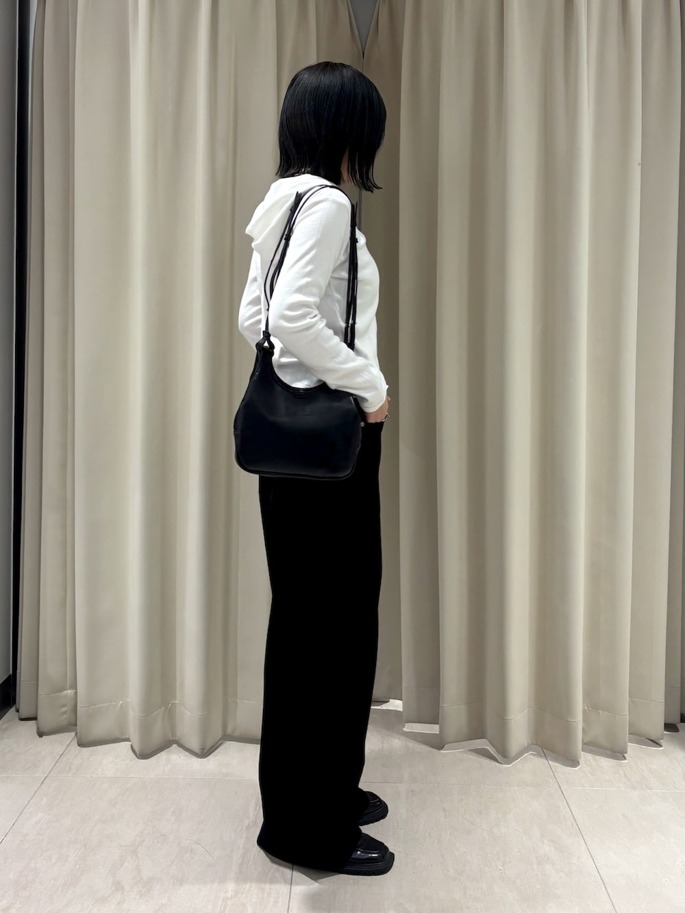 ホワイト系のパーカー、ブラック系のその他パンツ、ブラック系のショルダーバッグを着用したレディースの秋コーディネートの2枚目の写真