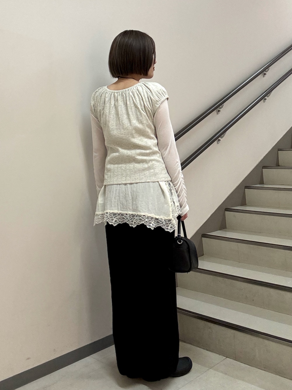 ブラック系のハンドバッグ、ブラック系のスカート、ベージュ系のTシャツ/カットソーを着用したレディースの春コーディネートの4枚目の写真