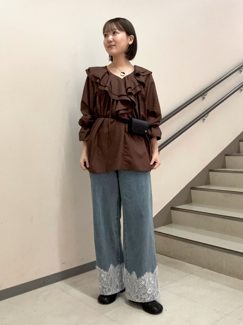 ブラウン系のワンピース、ブルー系のデニムパンツ、ブラック系のスリッポンを着用したレディースの夏コーディネートの4枚目の写真