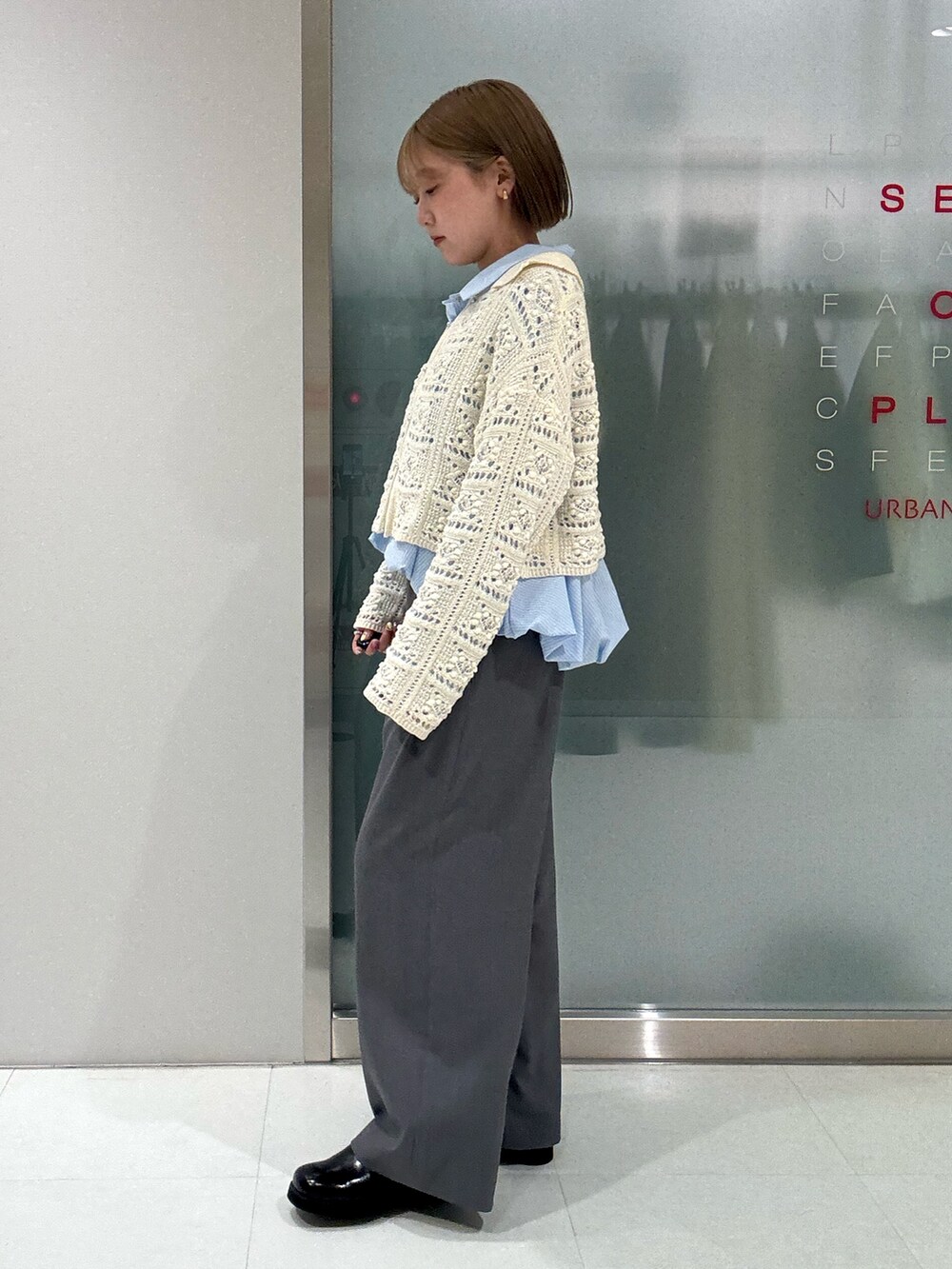 ホワイト系のカーディガン/ボレロ、ブルー系のシャツ/ブラウス、グレー系のスラックスを着用したレディースの春コーディネートの3枚目の写真