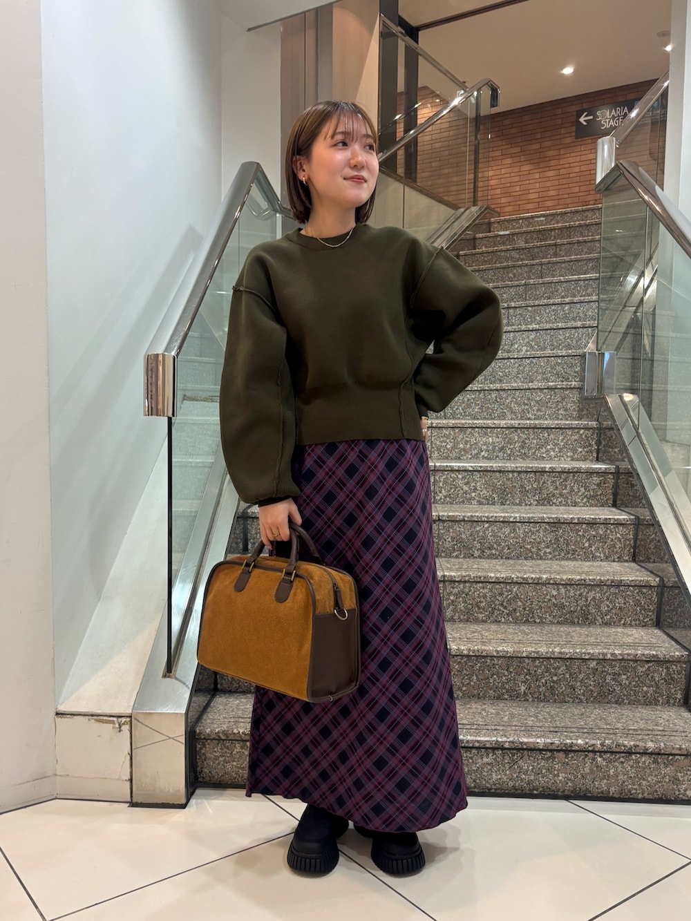 ブラック系のスニーカー、レッド系のスカート、イエロー系のボストンバッグを着用したレディースの冬コーディネートの2枚目の写真