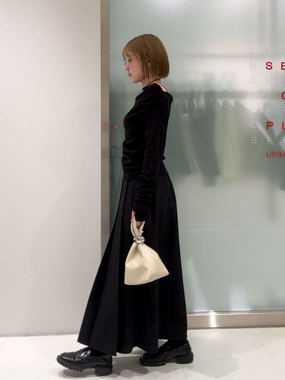 ブラック系のスカート、ベージュ系のハンドバッグ、ブラック系のTシャツ/カットソーを着用したレディースの春コーディネートの2枚目の写真