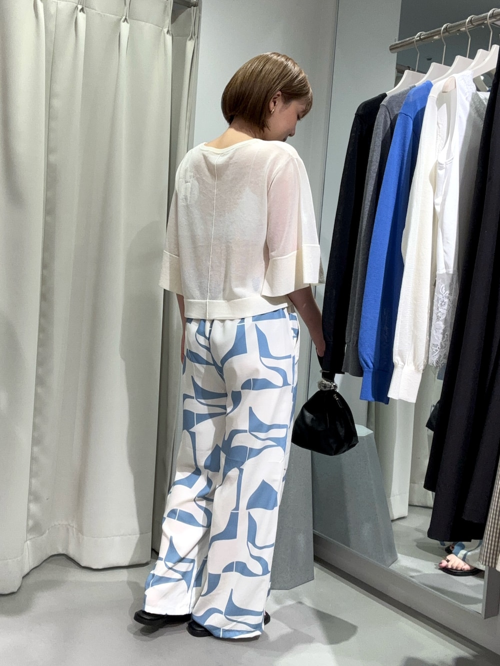 ブルー系のその他パンツ、ブラック系のハンドバッグ、ホワイト系のニット/セーターを着用したレディースの夏コーディネートの2枚目の写真