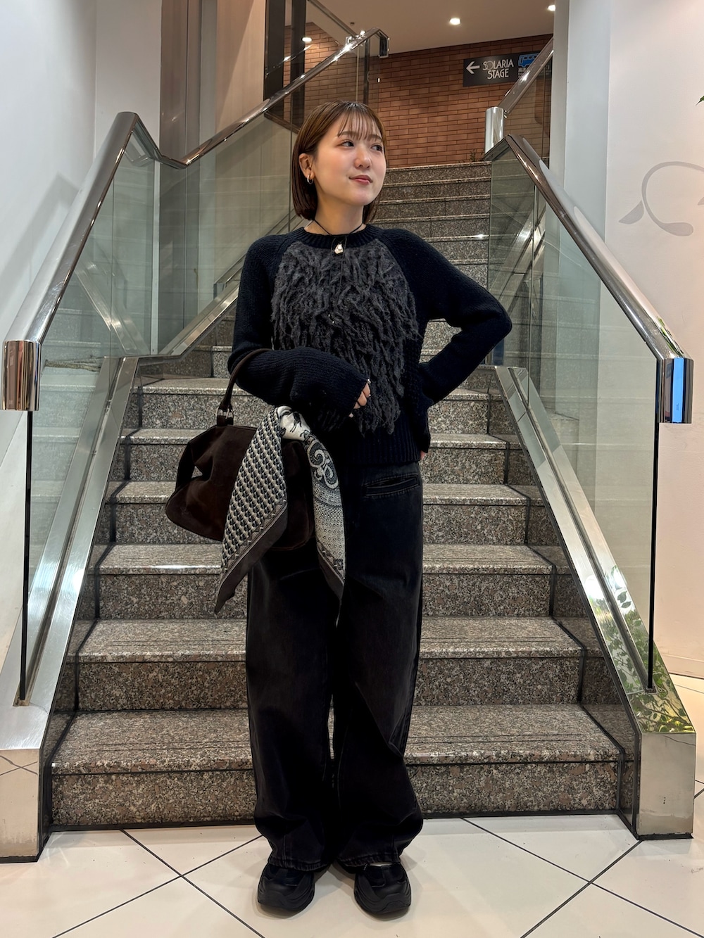 グレー系のニット/セーター、ブラック系のデニムパンツ、ブラウン系のボストンバッグを着用したレディースの冬コーディネートの2枚目の写真