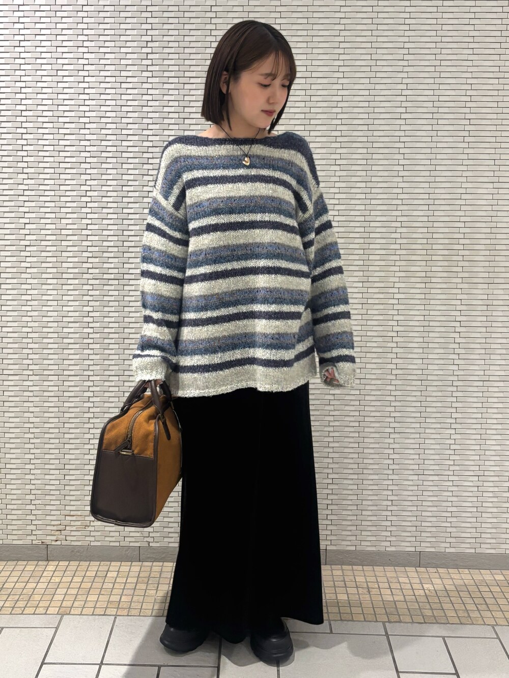 ブルー系のニット/セーター、ブラック系のスカート、イエロー系のボストンバッグを着用したレディースの秋コーディネートの2枚目の写真