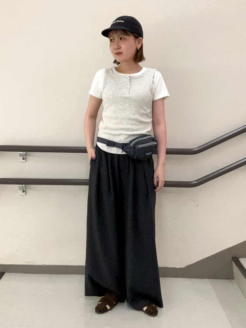 グレー系のタンクトップ、ホワイト系のTシャツ/カットソー、グレー系のスラックスを着用したレディースの夏コーディネートの2枚目の写真