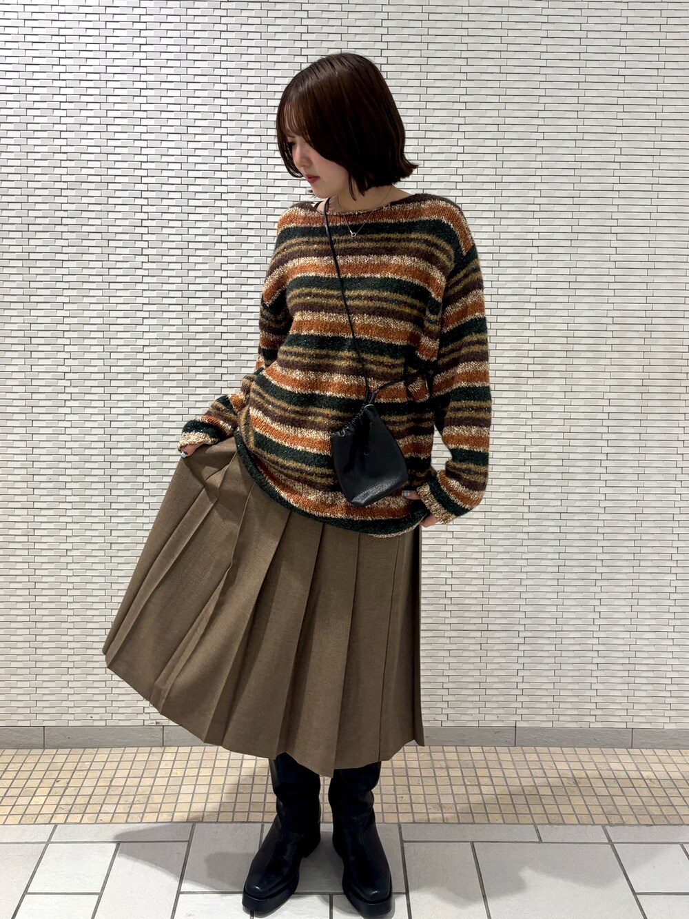 ブラック系のショルダーバッグ、ブラウン系のスカート、ブラウン系のニット/セーターを着用したレディースの秋コーディネートの4枚目の写真