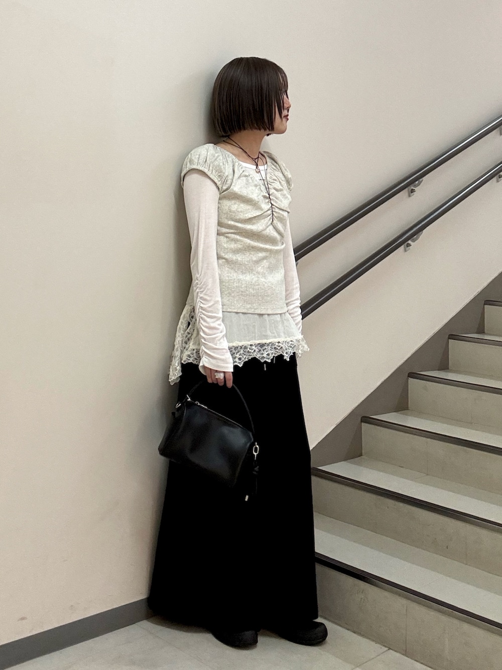 ブラック系のハンドバッグ、ブラック系のスカート、ベージュ系のTシャツ/カットソーを着用したレディースの春コーディネートの3枚目の写真