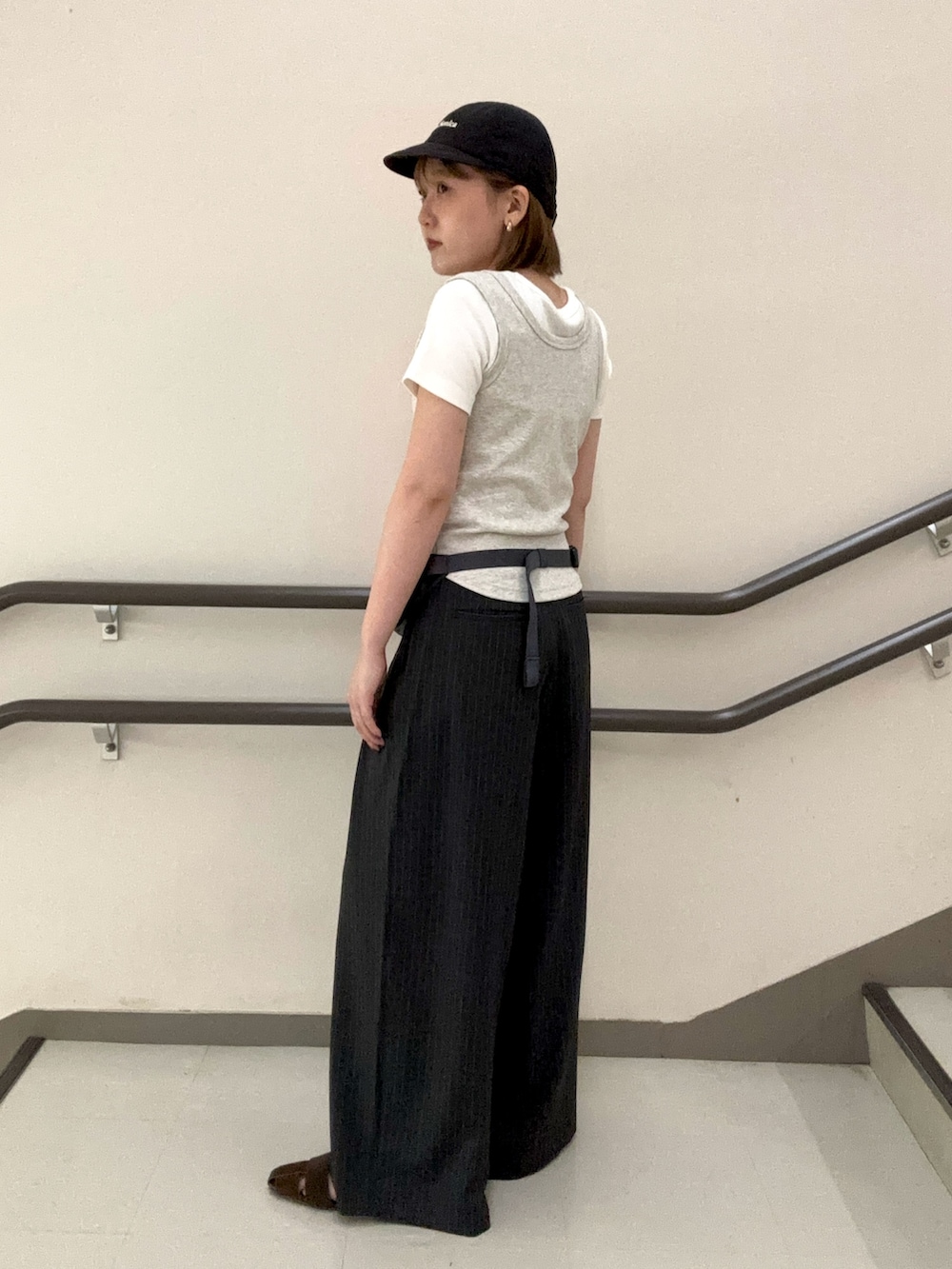 グレー系のタンクトップ、ホワイト系のTシャツ/カットソー、グレー系のスラックスを着用したレディースの夏コーディネートの4枚目の写真