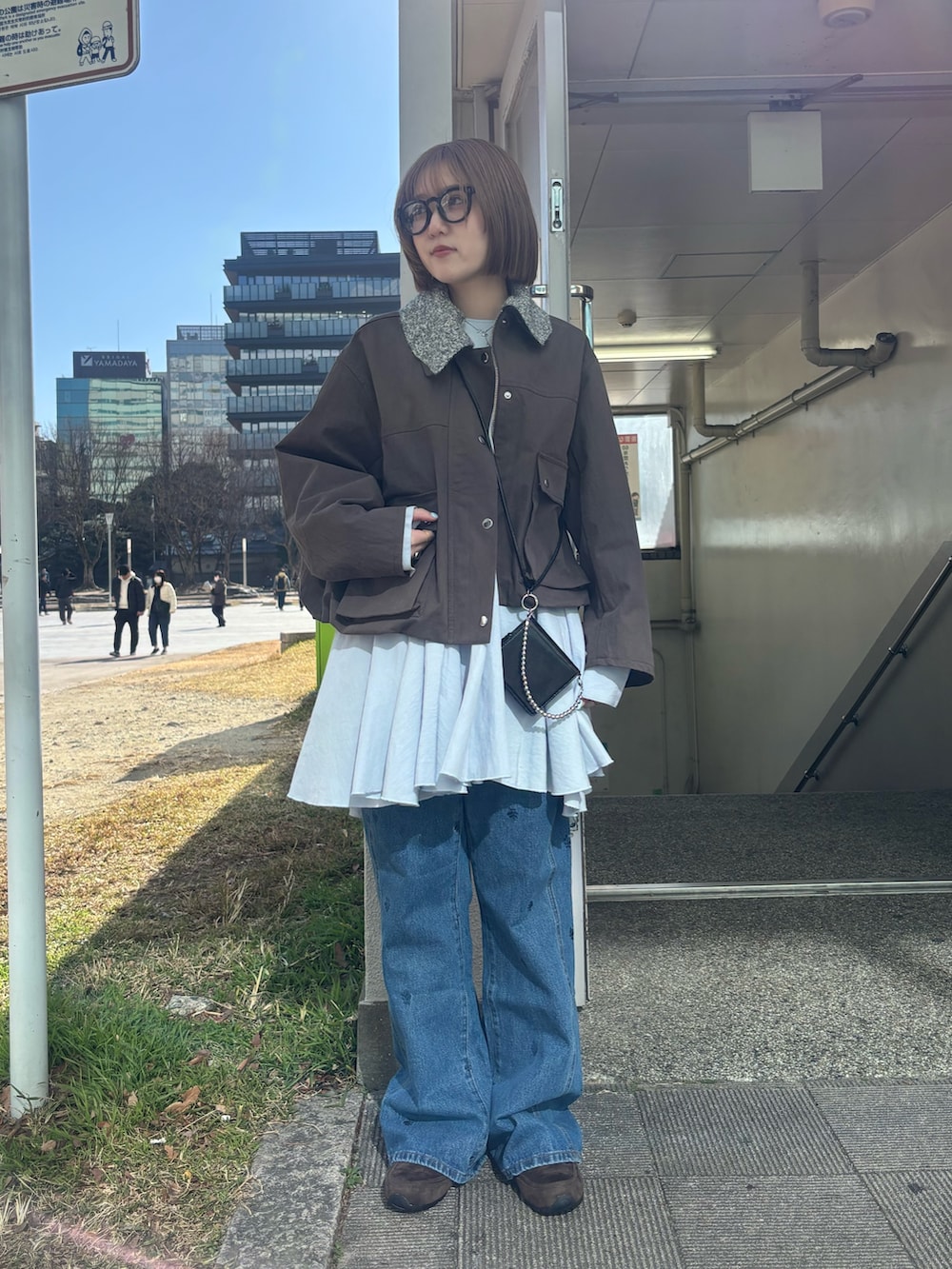 ブラウン系のブルゾン、ブルー系のワンピース、グレー系のスニーカーを着用したレディースの冬コーディネートの2枚目の写真