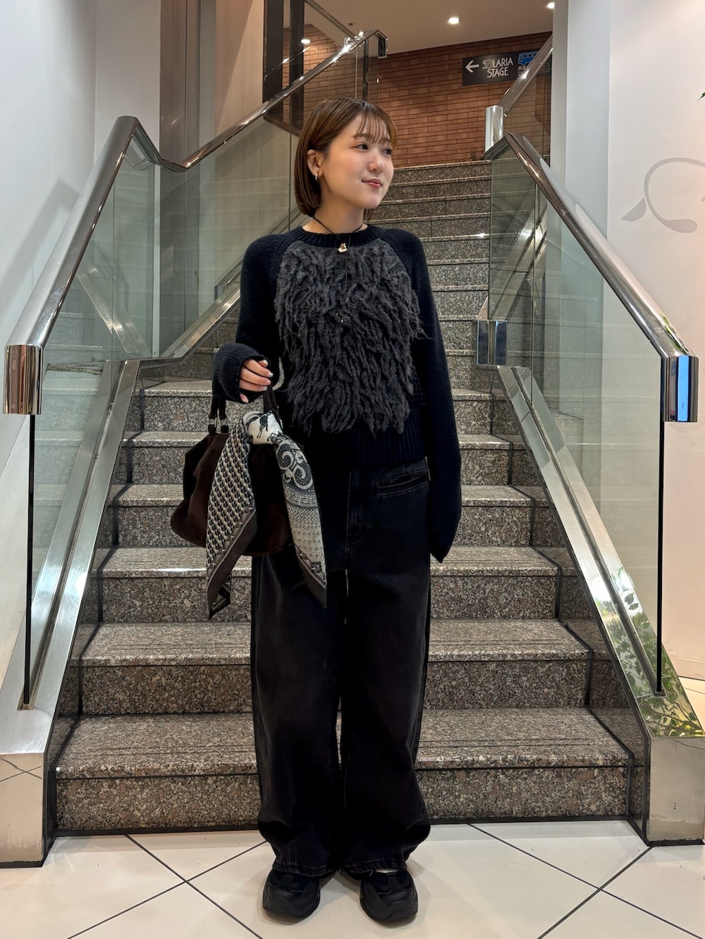 グレー系のニット/セーター、ブラック系のデニムパンツ、ブラウン系のボストンバッグを着用したレディースの冬コーディネートの3枚目の写真