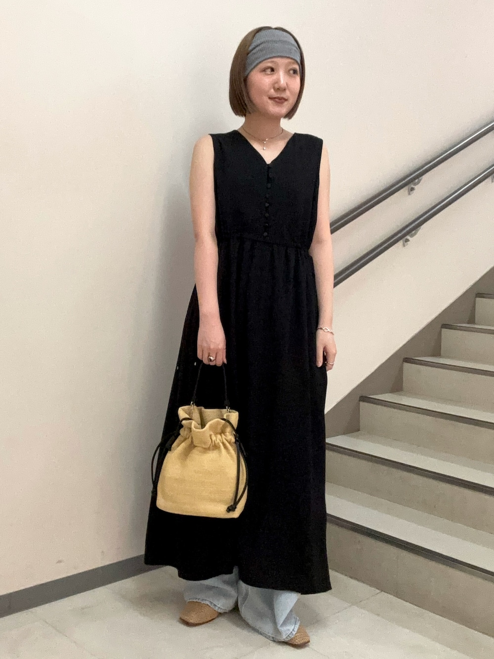 ブラック系のワンピース、ブルー系のデニムパンツ、ベージュ系のショルダーバッグを着用したレディースの夏コーディネートの4枚目の写真