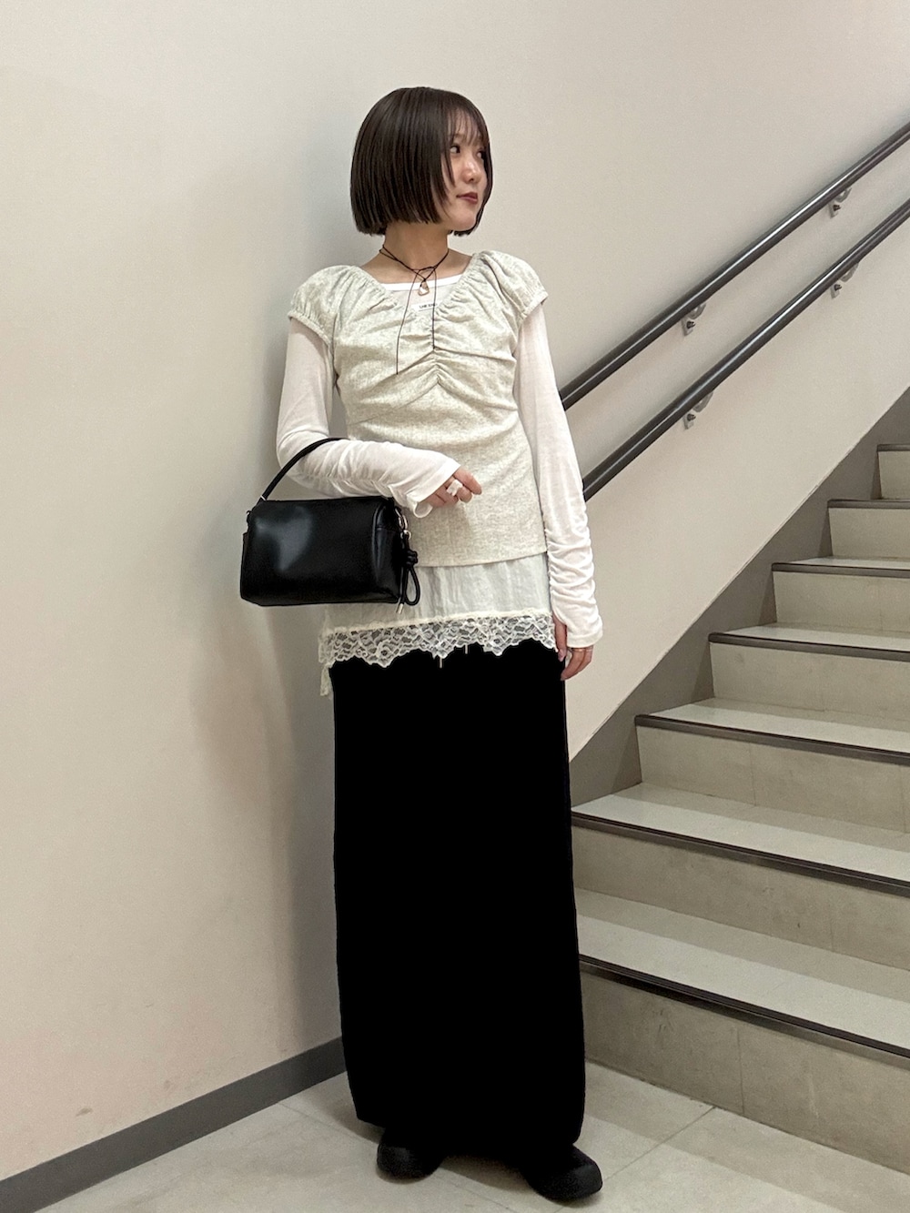 ブラック系のハンドバッグ、ブラック系のスカート、ベージュ系のTシャツ/カットソーを着用したレディースの春コーディネートの2枚目の写真