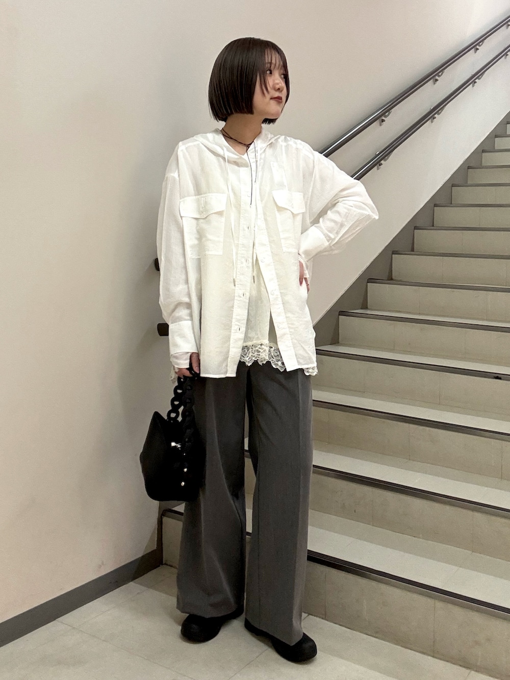 グレー系のスラックス、ブラック系のショルダーバッグ、ホワイト系のシャツ/ブラウスを着用したレディースの春コーディネートの3枚目の写真