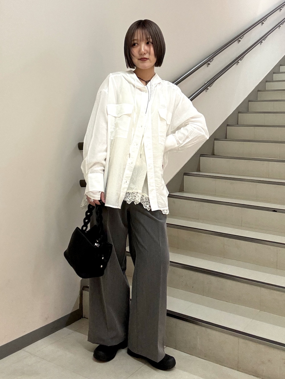 グレー系のスラックス、ブラック系のショルダーバッグ、ホワイト系のシャツ/ブラウスを着用したレディースの春コーディネートの4枚目の写真