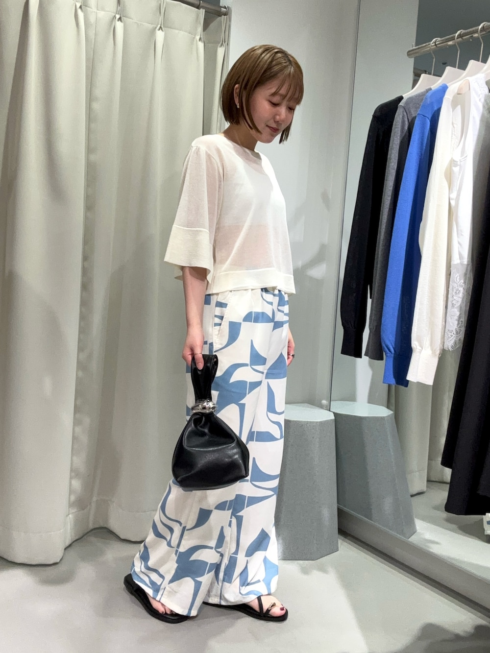 ブルー系のその他パンツ、ブラック系のハンドバッグ、ホワイト系のニット/セーターを着用したレディースの夏コーディネートの4枚目の写真