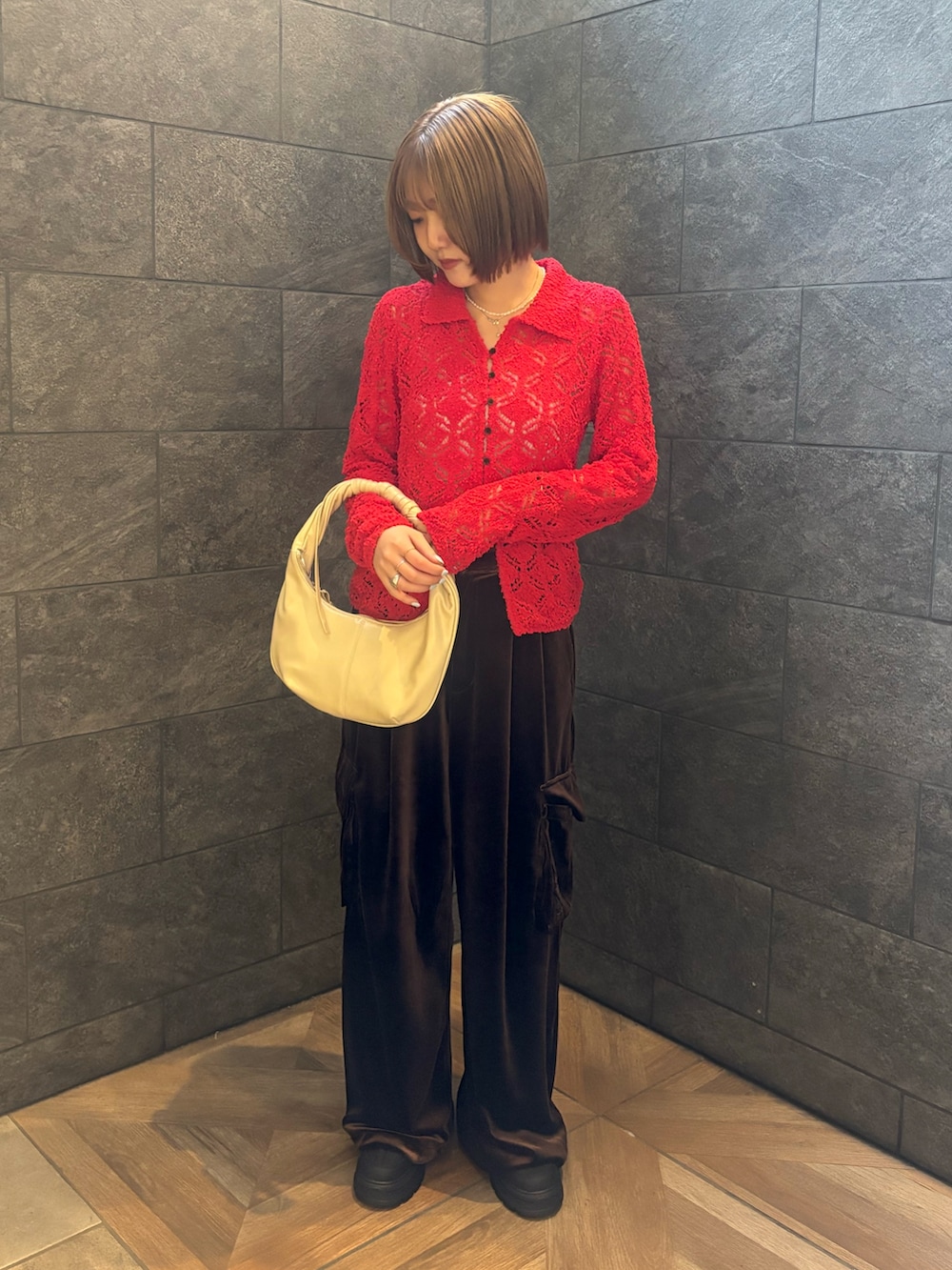 レッド系のニット/セーター、ブラウン系のその他パンツ、ホワイト系のハンドバッグを着用したレディースの冬コーディネートの2枚目の写真