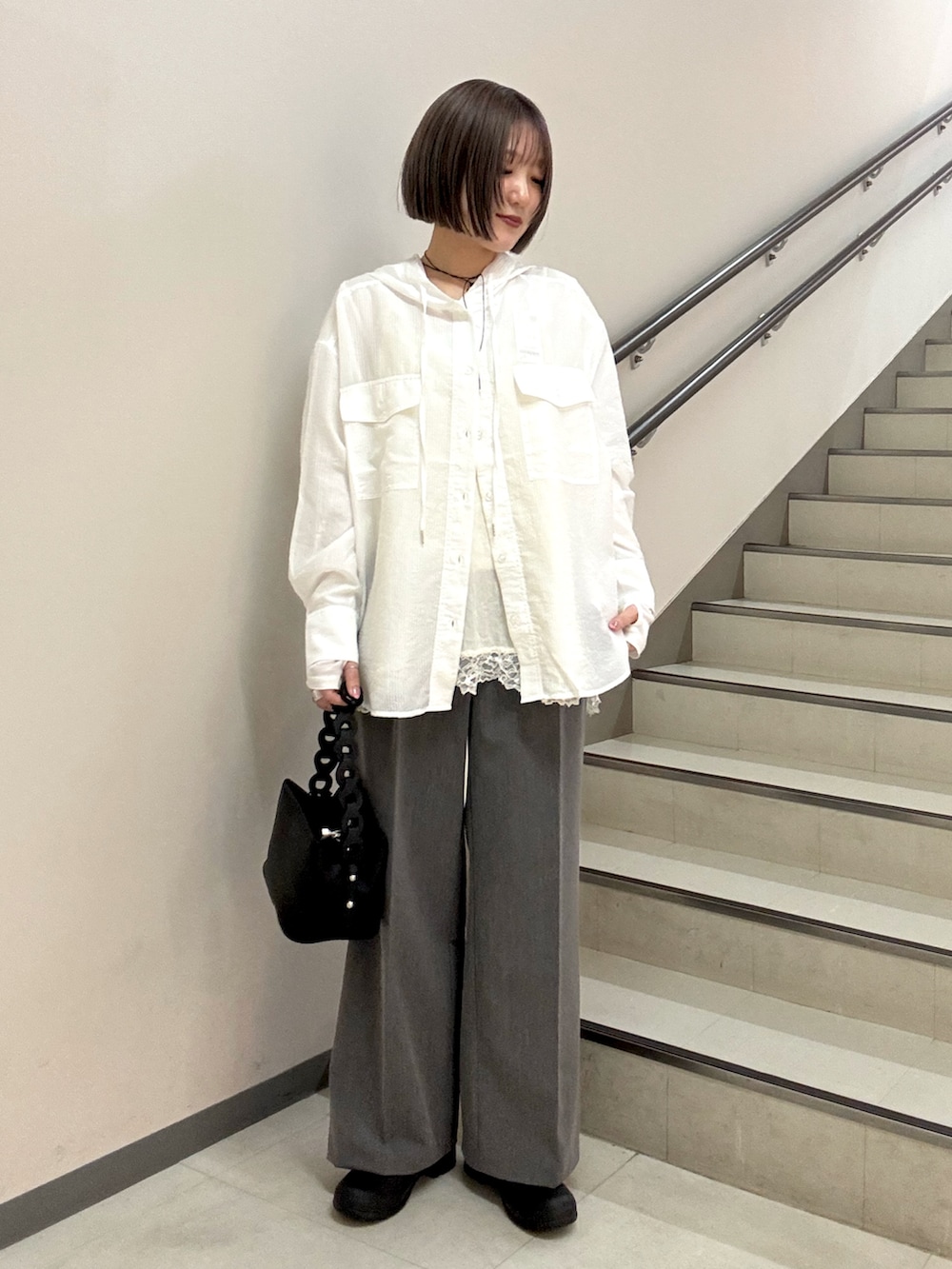 グレー系のスラックス、ブラック系のショルダーバッグ、ホワイト系のシャツ/ブラウスを着用したレディースの春コーディネートの2枚目の写真