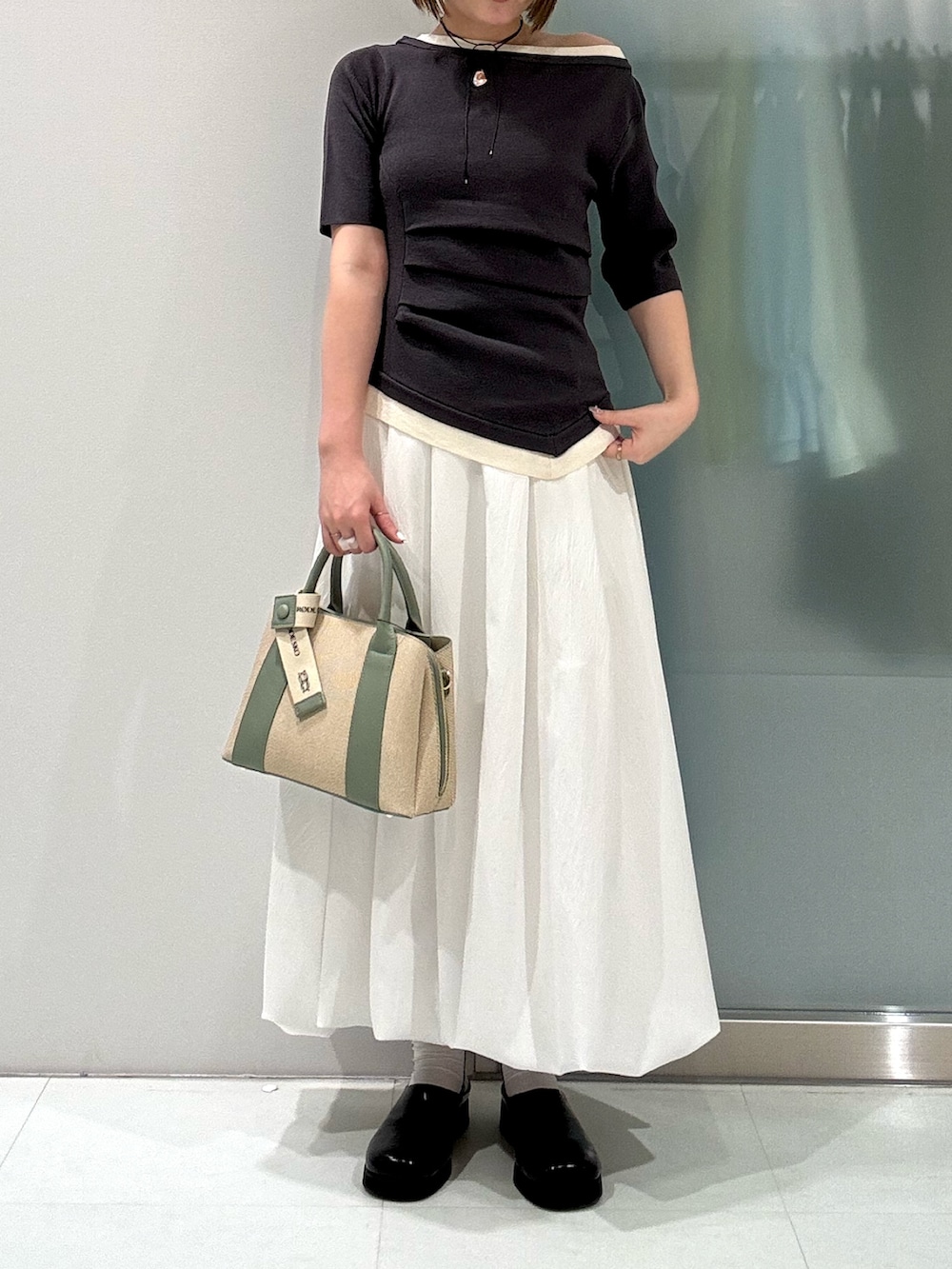 ホワイト系のスカート、ホワイト系のハンドバッグ、ブラック系のサンダルを着用したレディースの春コーディネートの4枚目の写真
