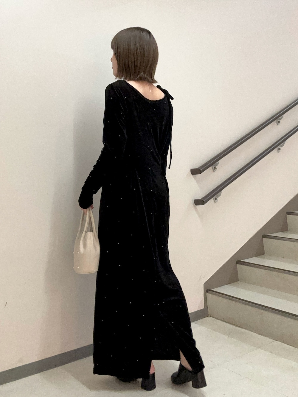 ブラック系のワンピース、ブラック系のスリッポン、ホワイト系のハンドバッグを着用したレディースの秋コーディネートの5枚目の写真