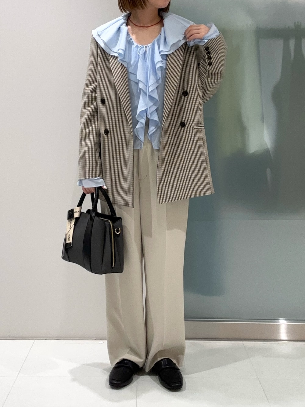 ブラック系のハンドバッグ、ベージュ系のその他パンツ、ブラック系のローファーを着用したレディースの春コーディネートの5枚目の写真