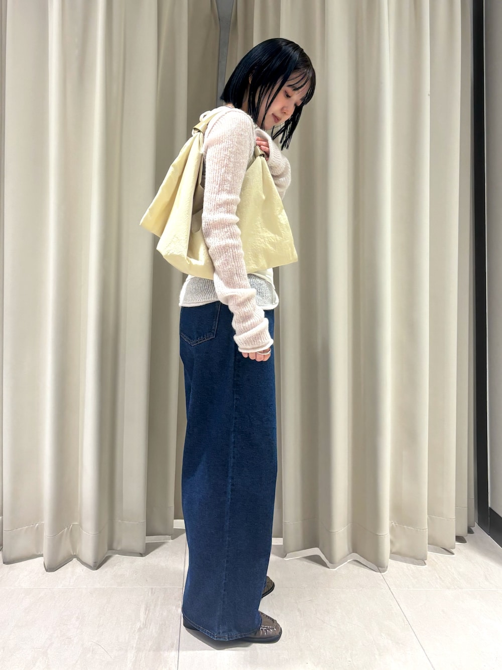 ホワイト系のニット/セーター、ブルー系のデニムパンツ、イエロー系のハンドバッグを着用したレディースの秋コーディネートの3枚目の写真