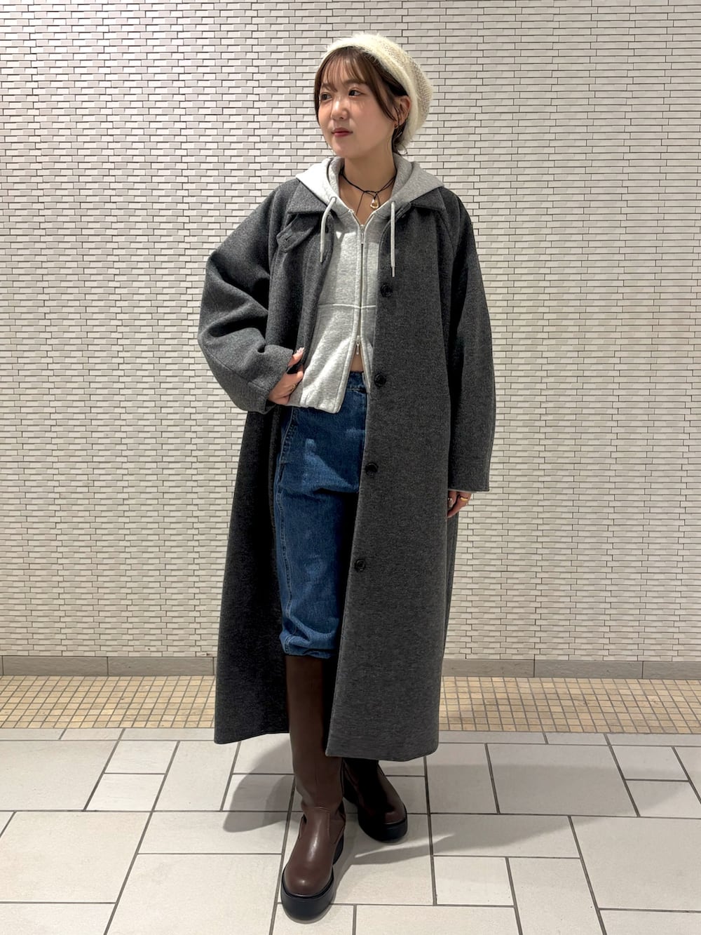 ブルー系のデニムパンツ、ブラウン系のブーツ、グレー系のパーカーを着用したレディースの秋コーディネートの2枚目の写真