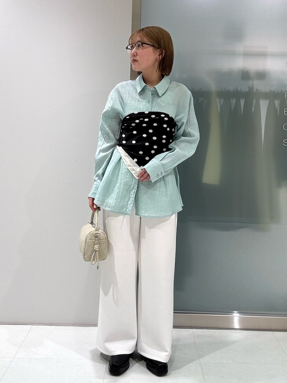 ベージュ系のハンドバッグ、ホワイト系のその他パンツ、グリーン系のシャツ/ブラウスを着用したレディースの春コーディネートの2枚目の写真