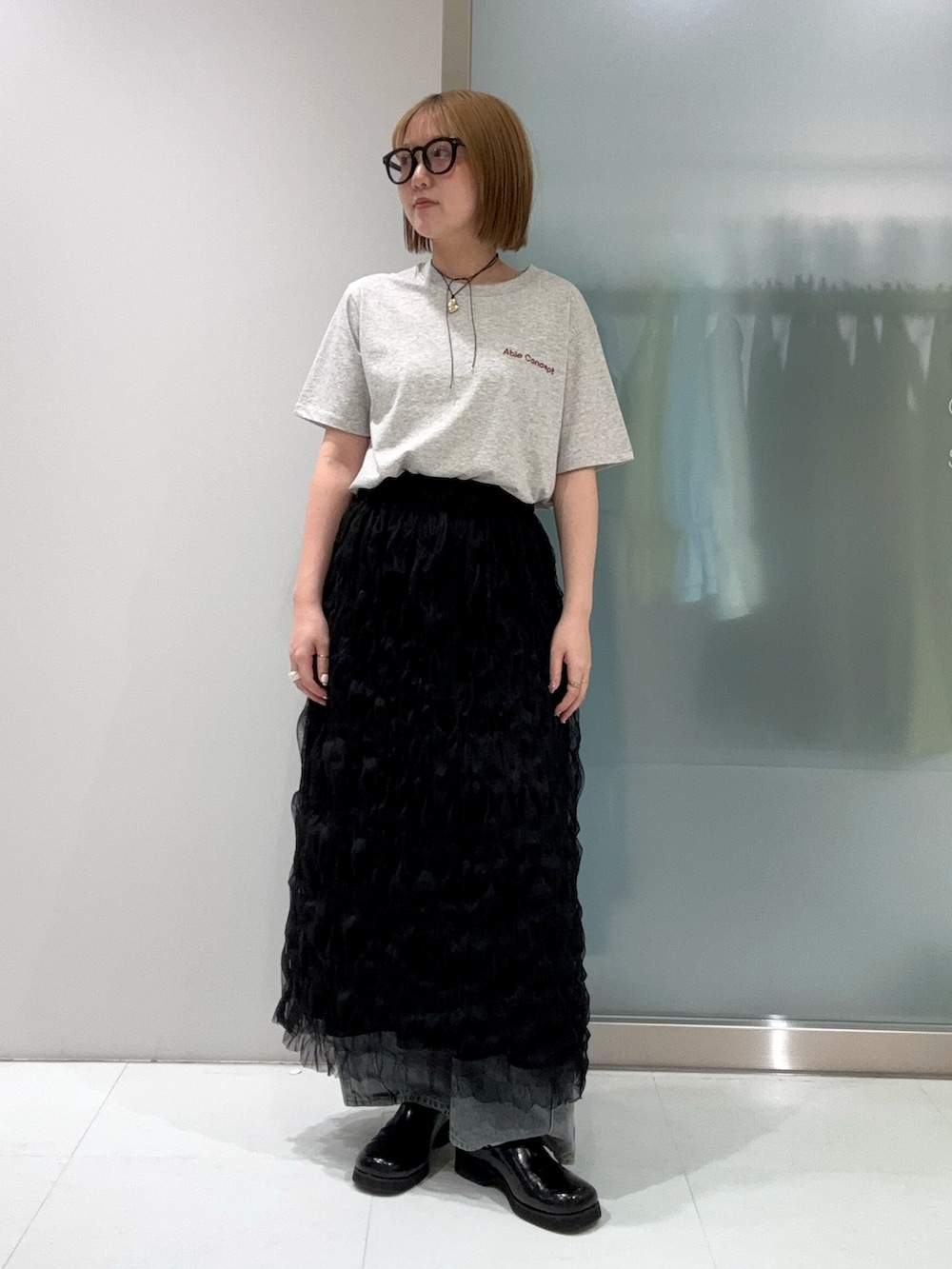 ブルー系のデニムパンツ、ブラック系のスカート、ブラック系のサンダルを着用したレディースの春コーディネートの2枚目の写真