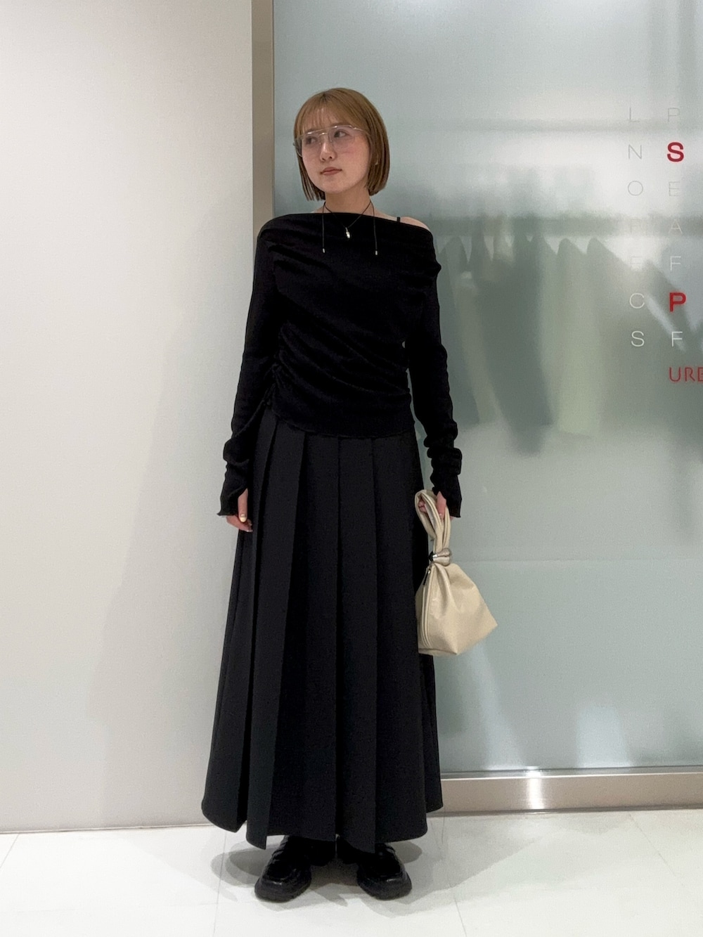 ブラック系のスカート、ベージュ系のハンドバッグ、ブラック系のTシャツ/カットソーを着用したレディースの春コーディネートの4枚目の写真