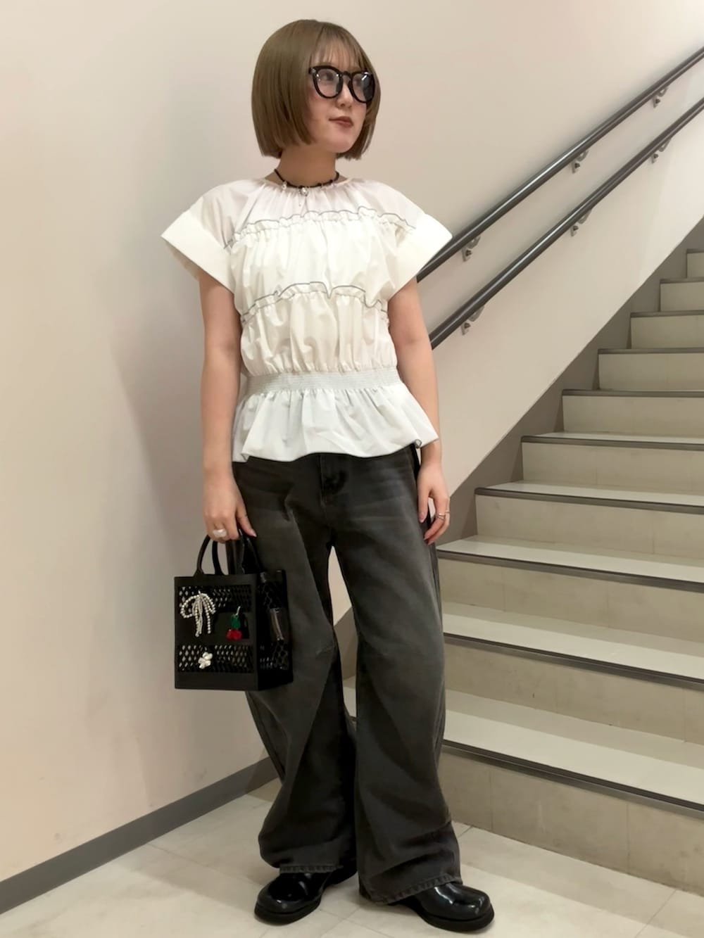 グレー系のデニムパンツ、ホワイト系のシャツ/ブラウス、ブラック系のハンドバッグを着用したレディースの春コーディネートの3枚目の写真
