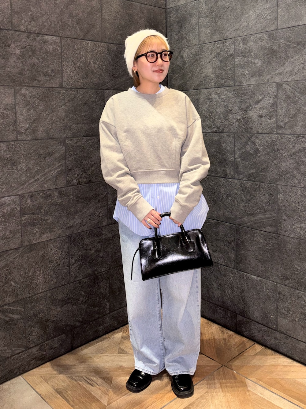 ブラック系のボストンバッグ、ブルー系のデニムパンツ、ベージュ系のスウェットを着用したレディースの冬コーディネートの3枚目の写真