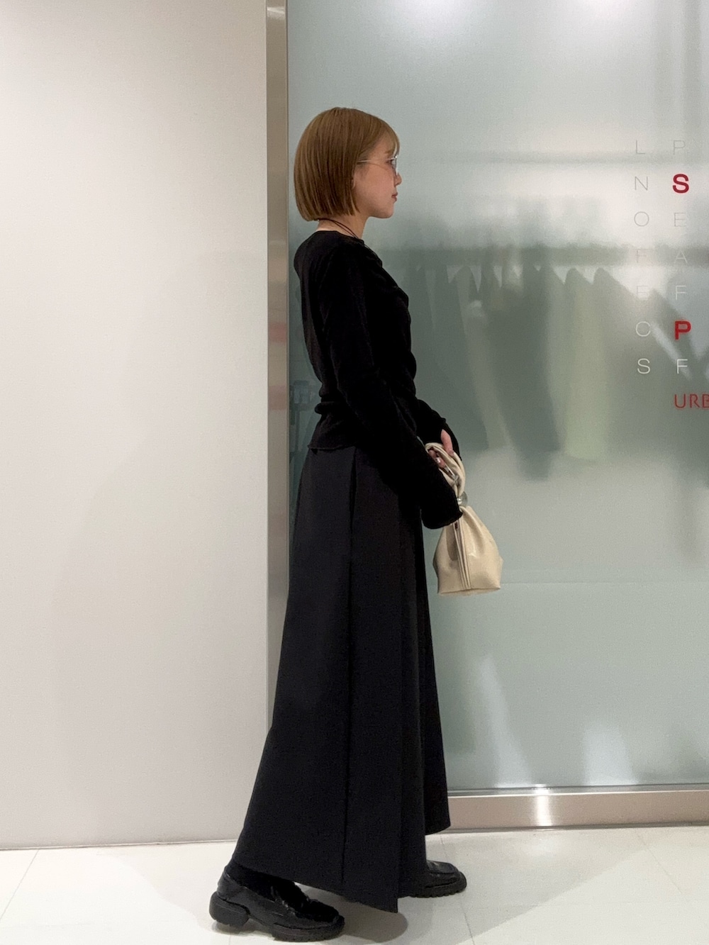 ブラック系のスカート、ベージュ系のハンドバッグ、ブラック系のTシャツ/カットソーを着用したレディースの春コーディネートの3枚目の写真