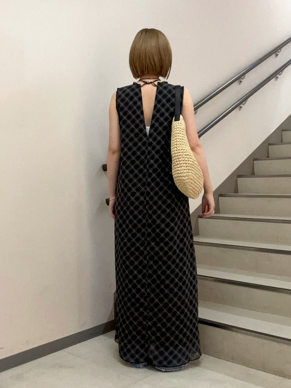 ブラック系のワンピース、ベージュ系のサンダル、ブルー系のデニムパンツを着用したレディースの春コーディネートの4枚目の写真