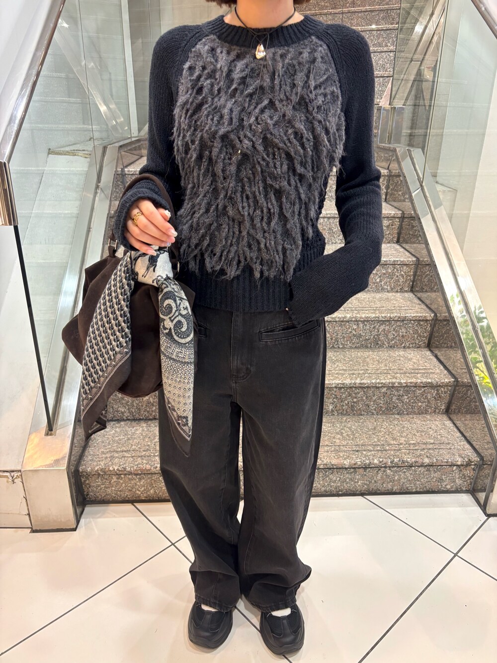 グレー系のニット/セーター、ブラック系のデニムパンツ、ブラウン系のボストンバッグを着用したレディースの冬コーディネートの5枚目の写真