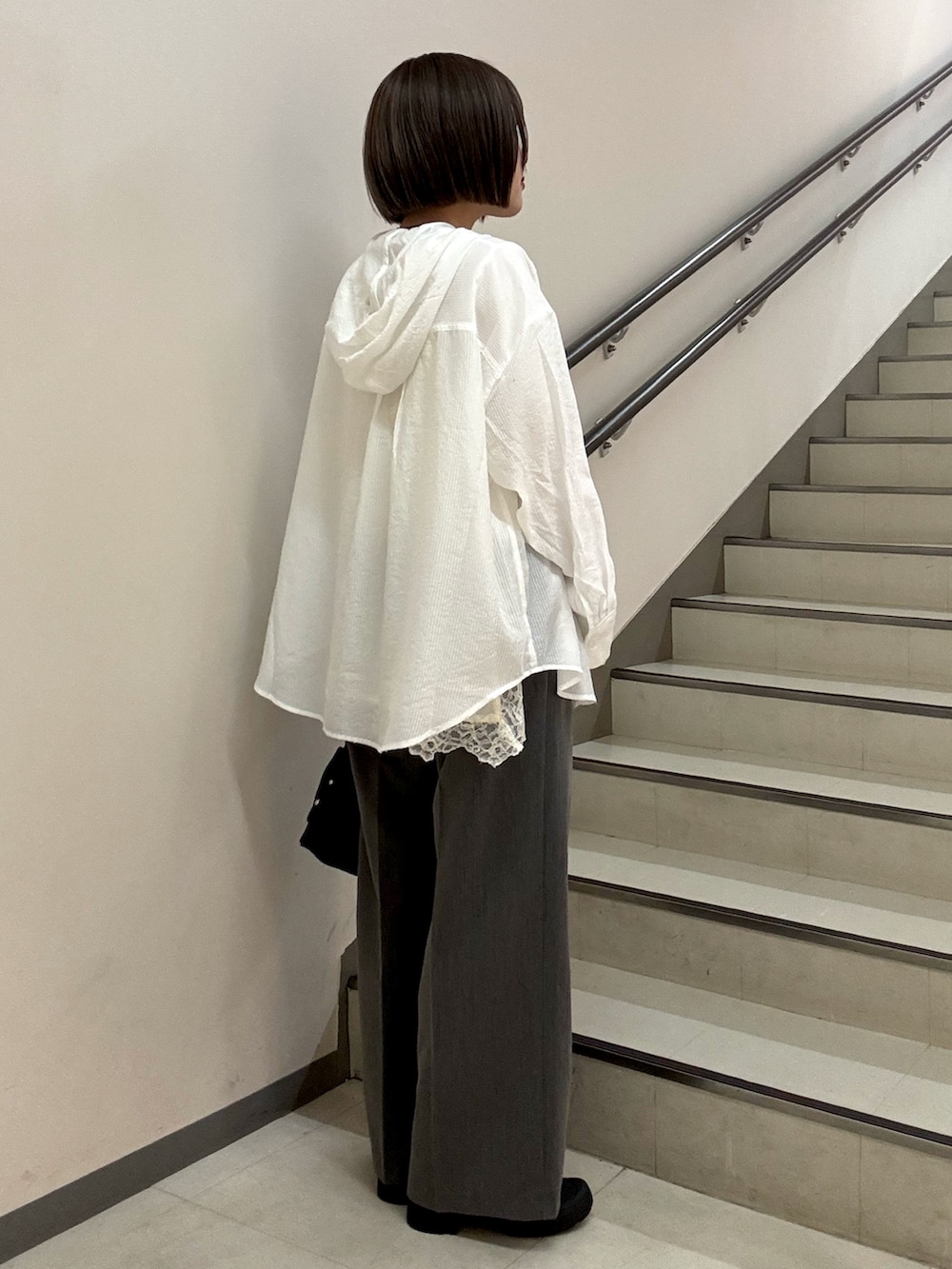 グレー系のスラックス、ブラック系のショルダーバッグ、ホワイト系のシャツ/ブラウスを着用したレディースの春コーディネートの5枚目の写真