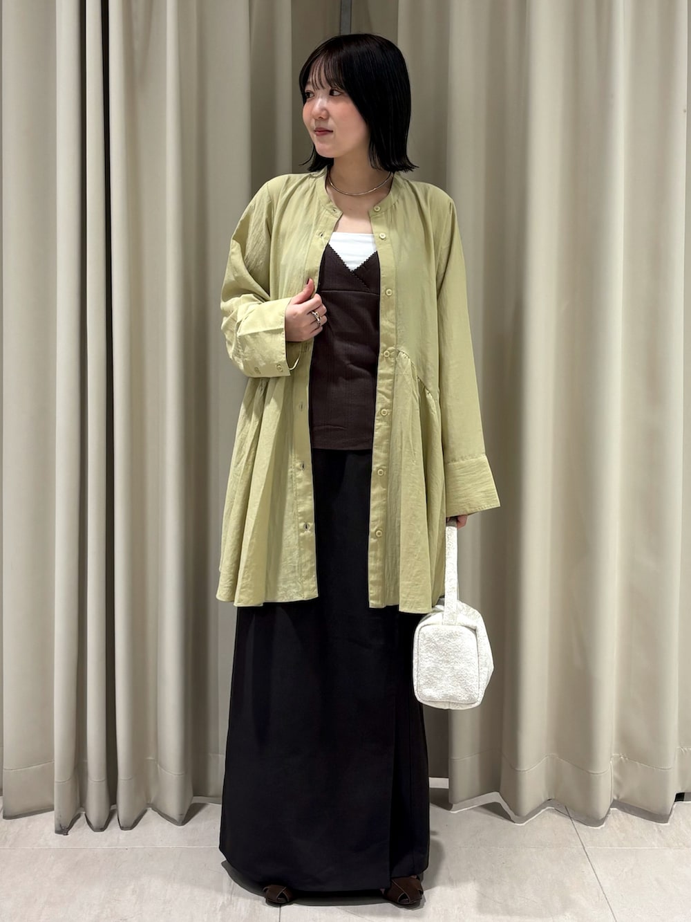 ブラウン系のTシャツ/カットソー、ブラウン系のスカート、ホワイト系のハンドバッグを着用したレディースの秋コーディネートの6枚目の写真