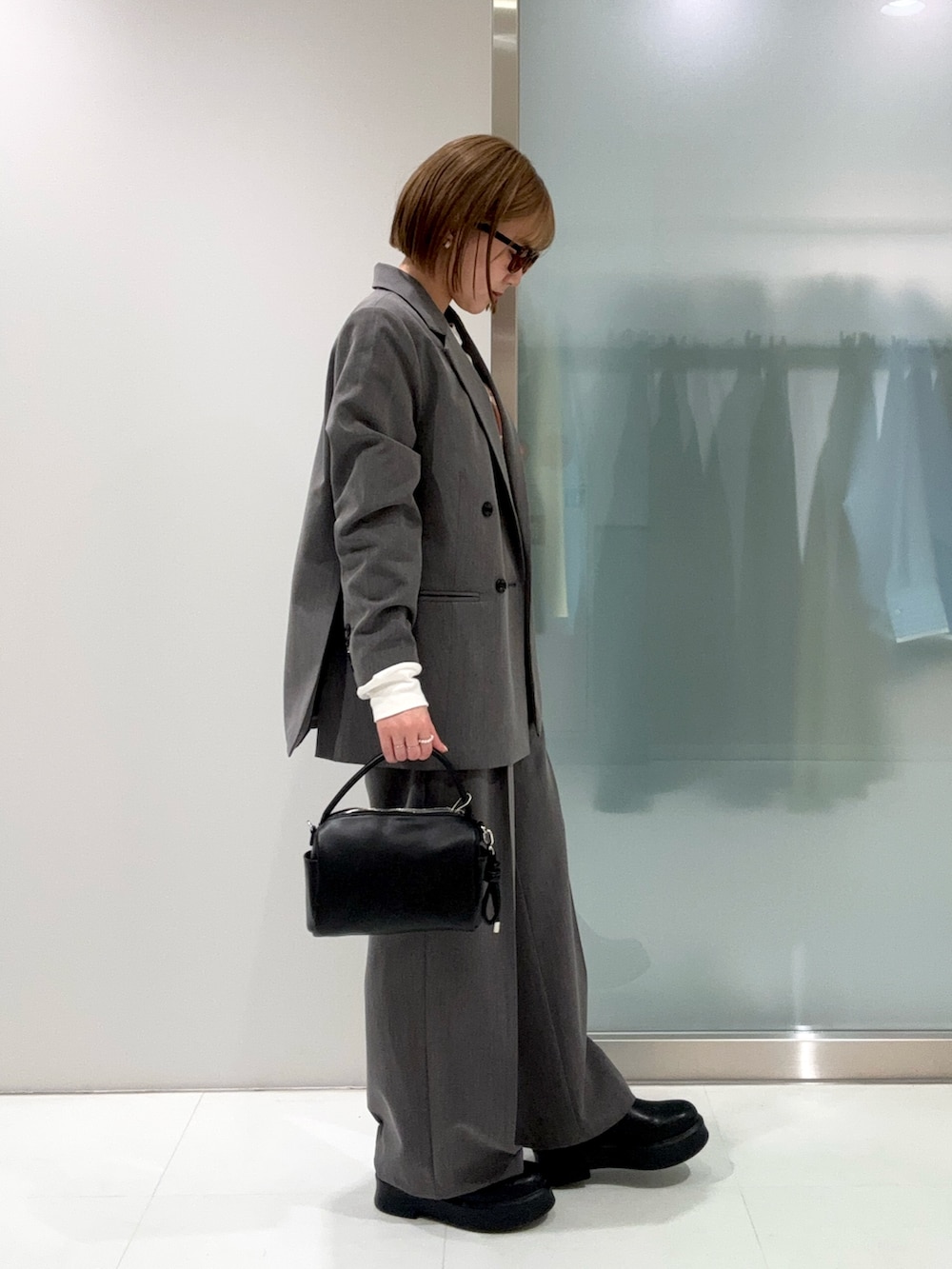 グレー系のスラックス、ブラック系のハンドバッグ、ブラック系のその他シューズを着用したレディースの春コーディネートの4枚目の写真
